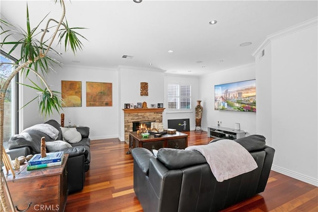 living area with a fireplace, visible vents, ornamental molding, wood finished floors, and baseboards