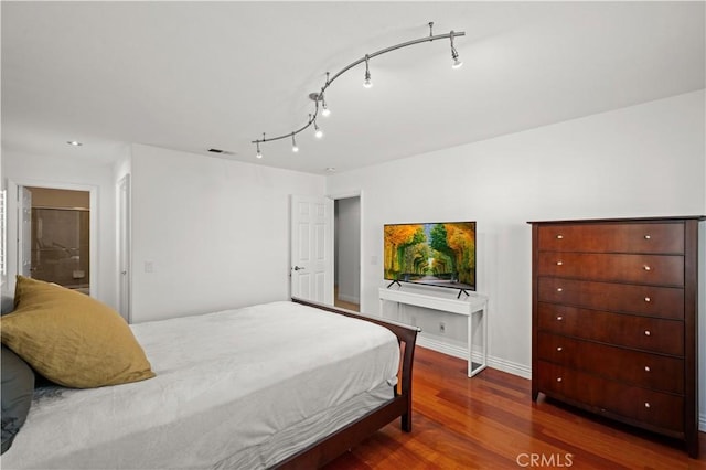 bedroom featuring rail lighting, baseboards, visible vents, and dark wood finished floors