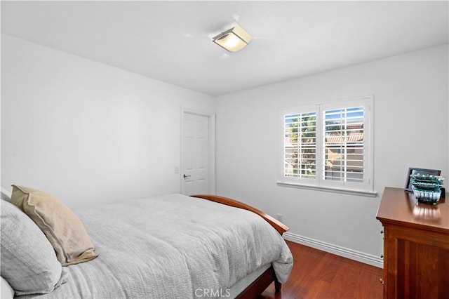 bedroom with baseboards and dark wood-type flooring