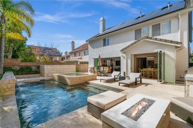 rear view of house featuring a fenced in pool, outdoor dining area, an outdoor fire pit, a patio area, and an in ground hot tub