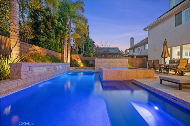 pool at dusk with a fenced in pool, a patio area, a fenced backyard, and outdoor dining area