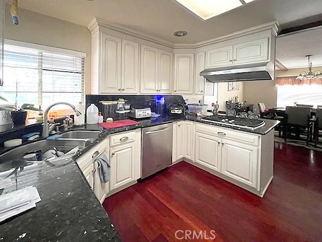 kitchen featuring white cabinets, appliances with stainless steel finishes, dark stone countertops, a peninsula, and under cabinet range hood