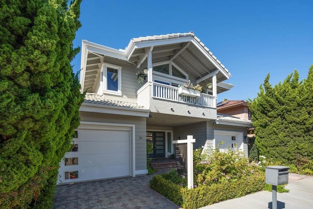 view of front facade with a tile roof, driveway, a balcony, and an attached garage