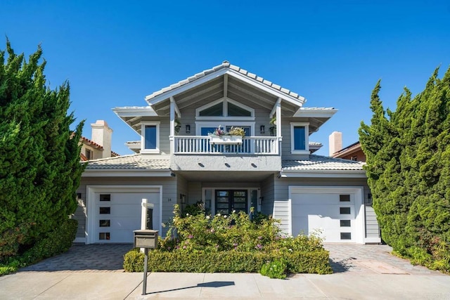 view of front facade featuring decorative driveway, an attached garage, and a balcony