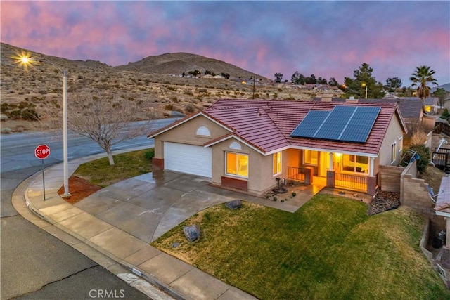 ranch-style home with a yard, roof mounted solar panels, a mountain view, and a tiled roof