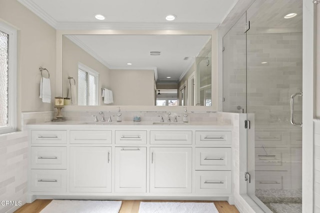 full bathroom with a stall shower, crown molding, a sink, and wood finished floors