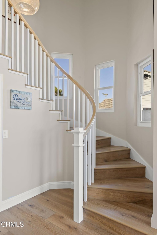 stairs featuring plenty of natural light, baseboards, and wood finished floors