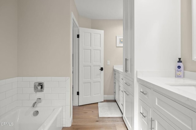 bathroom featuring a garden tub, wood finished floors, and vanity