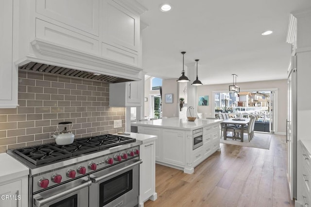 kitchen with white cabinetry, light countertops, appliances with stainless steel finishes, hanging light fixtures, and a center island