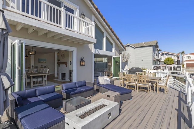 deck featuring outdoor dining space, an outdoor living space with a fire pit, a residential view, and grilling area