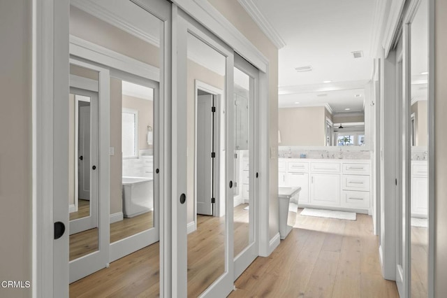 corridor featuring french doors, recessed lighting, ornamental molding, a sink, and light wood-type flooring