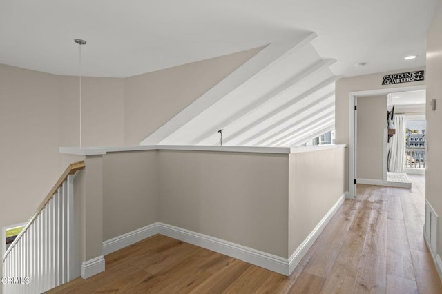 hallway with baseboards, light wood finished floors, and an upstairs landing