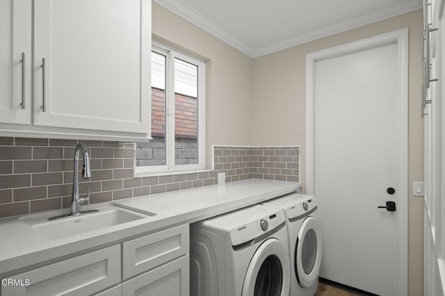 laundry area featuring crown molding, cabinet space, a sink, and washer and clothes dryer