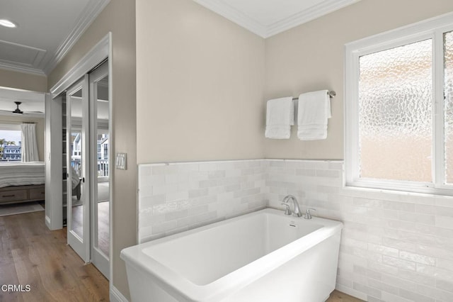 bathroom featuring a soaking tub, ensuite bath, ornamental molding, wood finished floors, and tile walls