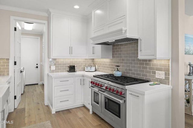 kitchen featuring double oven range, light countertops, light wood finished floors, and white cabinets