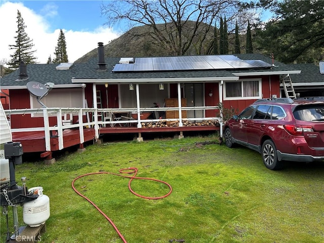 view of front of house featuring solar panels, a front lawn, and a shingled roof