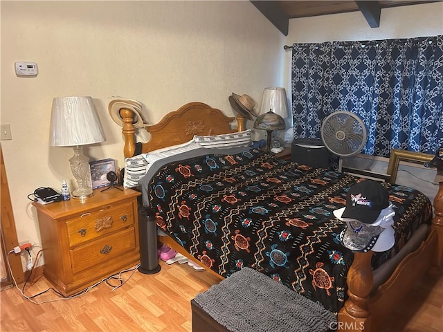 bedroom featuring beam ceiling and wood finished floors