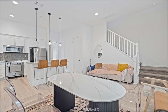 living room with light wood-style floors, recessed lighting, visible vents, and stairs