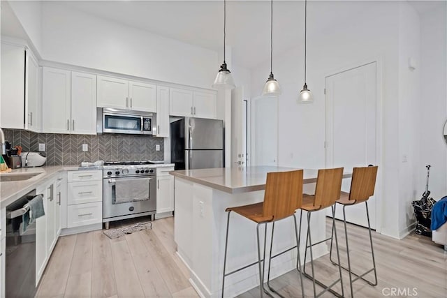 kitchen featuring stainless steel appliances, a kitchen island, light countertops, and white cabinets