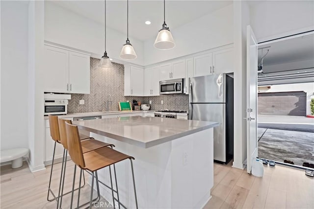 kitchen with light countertops, appliances with stainless steel finishes, a kitchen island, and white cabinetry