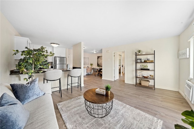 living area with light wood-style flooring, baseboards, and a wall mounted AC