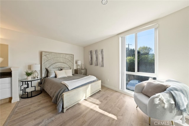 bedroom featuring vaulted ceiling, light wood finished floors, and baseboards