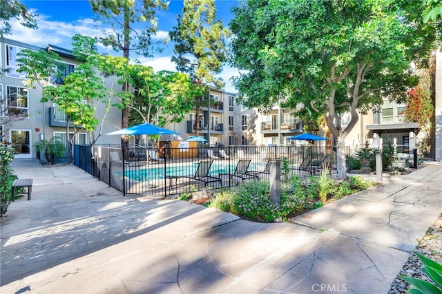 view of community featuring a residential view, fence, a swimming pool, and a patio