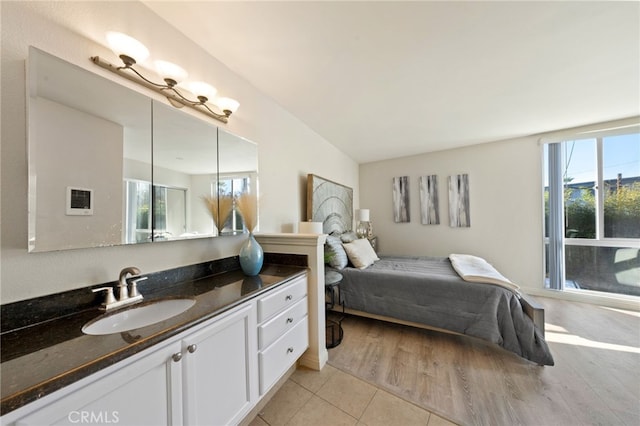 bedroom with light tile patterned floors, multiple windows, and a sink