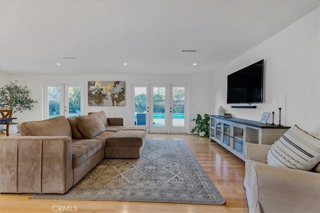 living area featuring plenty of natural light, visible vents, wood finished floors, and french doors