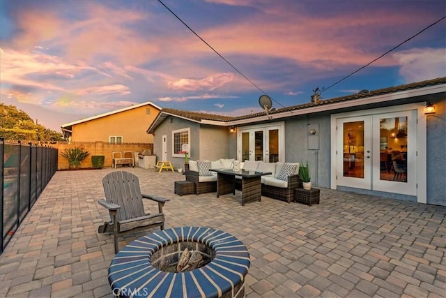 rear view of property with an outdoor living space with a fire pit, a patio, a fenced backyard, french doors, and stucco siding