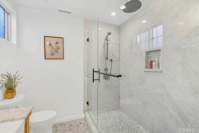 bathroom with a marble finish shower, visible vents, toilet, vanity, and baseboards