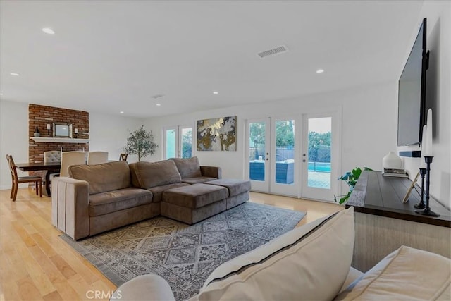 living room with light wood-style floors, recessed lighting, visible vents, and french doors