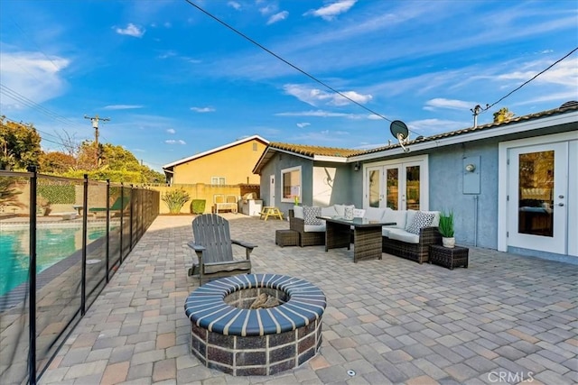 view of patio with an outdoor living space with a fire pit, french doors, fence, and a fenced in pool