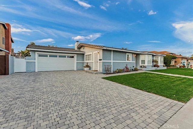 ranch-style house featuring decorative driveway, stucco siding, a front yard, fence, and a garage