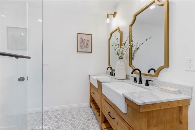 bathroom with double vanity, walk in shower, a sink, and baseboards