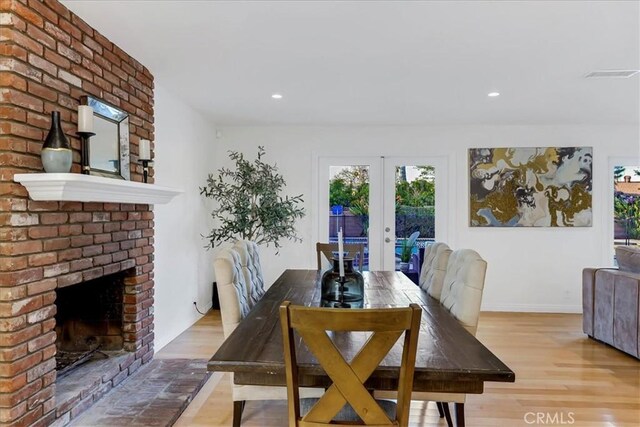 unfurnished dining area with recessed lighting, wood finished floors, visible vents, french doors, and a brick fireplace