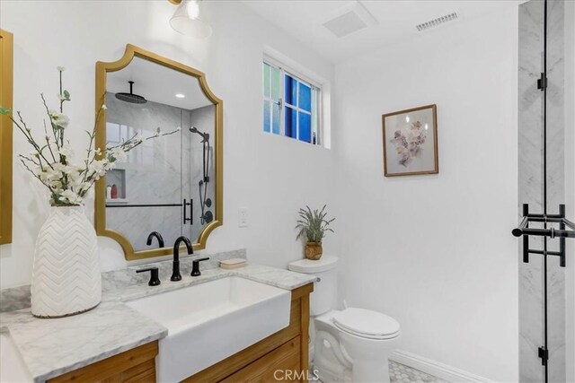 bathroom featuring visible vents, toilet, vanity, and a marble finish shower