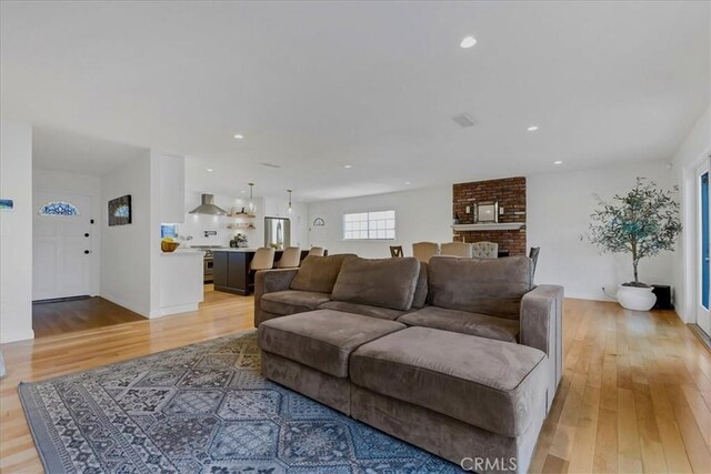 living area featuring a brick fireplace, light wood-style flooring, and recessed lighting