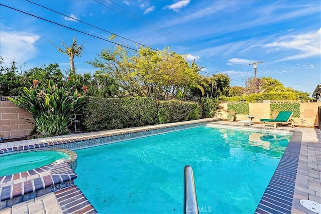 view of swimming pool with a fenced backyard and a pool with connected hot tub