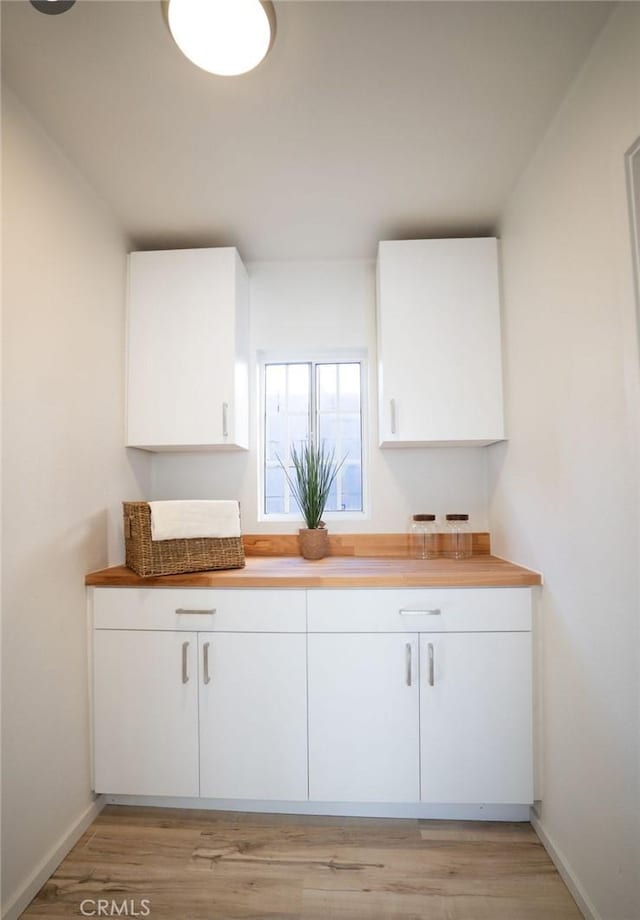 kitchen featuring baseboards, light wood-style floors, and white cabinets