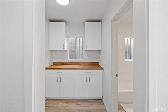 kitchen with butcher block countertops, white cabinets, and light wood-style flooring