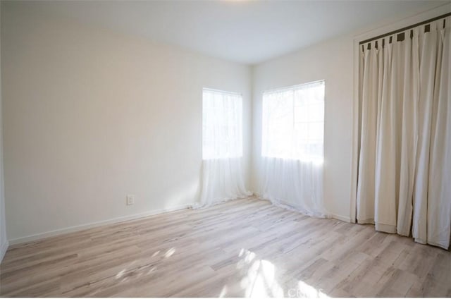 unfurnished room with light wood finished floors and baseboards