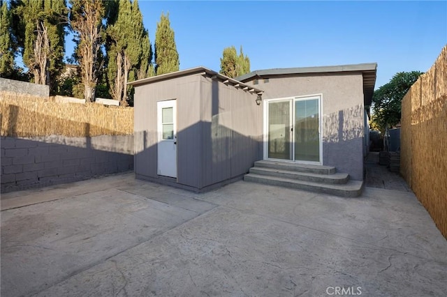 rear view of house with entry steps, a patio area, and a fenced backyard