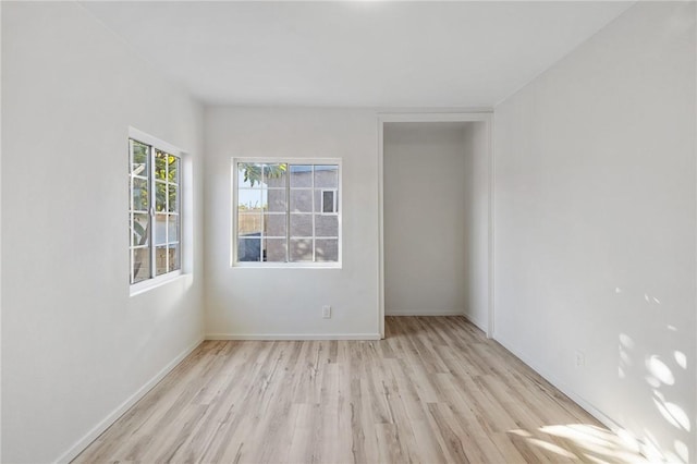 unfurnished room with light wood-type flooring and baseboards