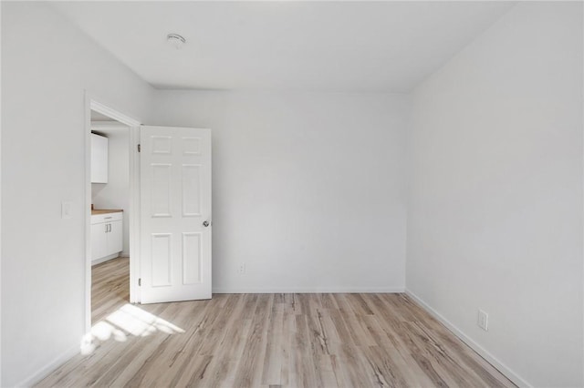 spare room featuring light wood-type flooring and baseboards