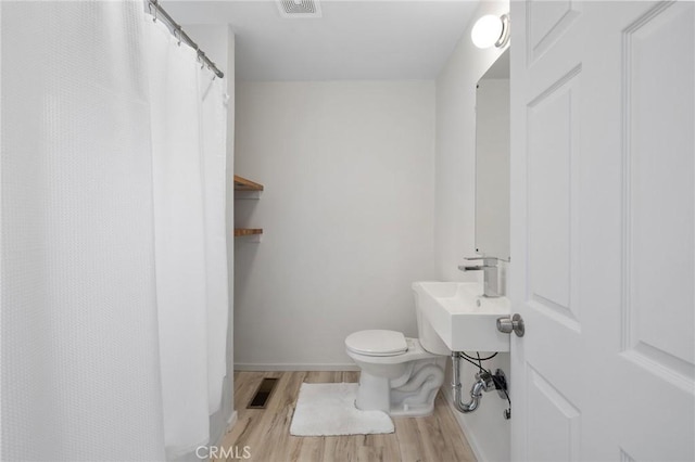 full bath with toilet, a sink, visible vents, and wood finished floors