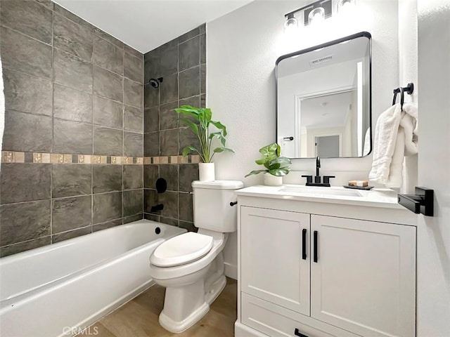 full bathroom with shower / bath combination, visible vents, toilet, wood finished floors, and vanity