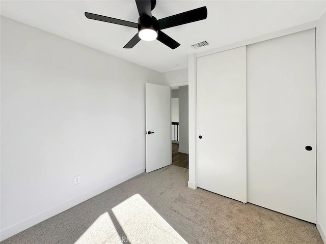 unfurnished bedroom with a closet, visible vents, light carpet, ceiling fan, and baseboards