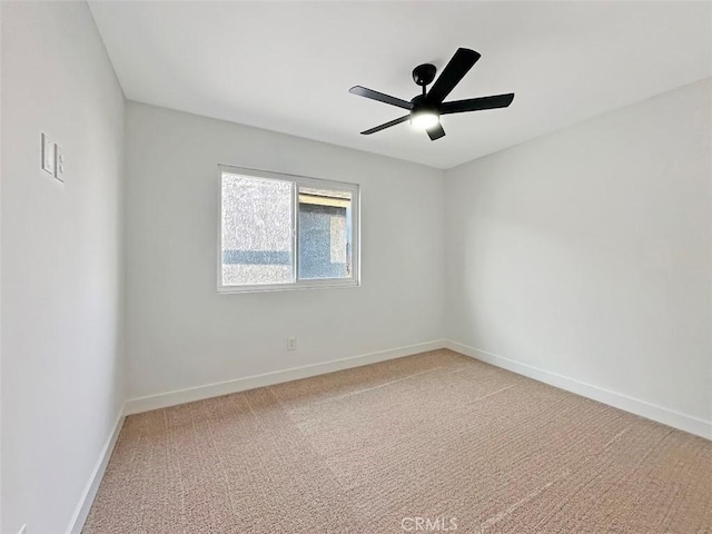 carpeted spare room featuring ceiling fan and baseboards