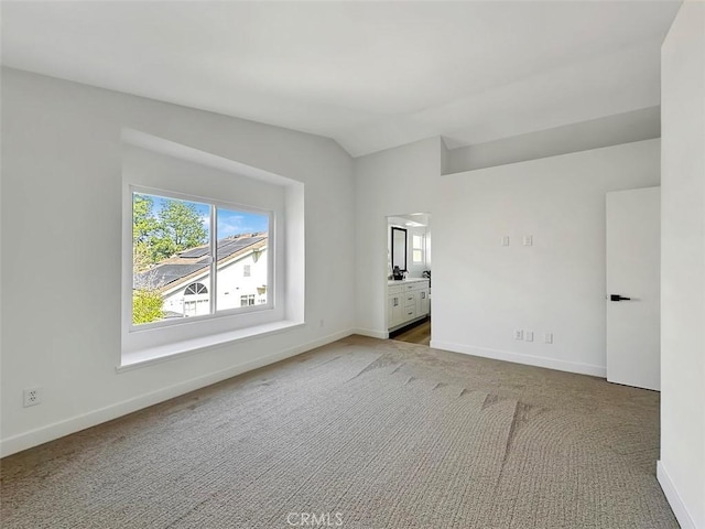 spare room with lofted ceiling, light colored carpet, and baseboards